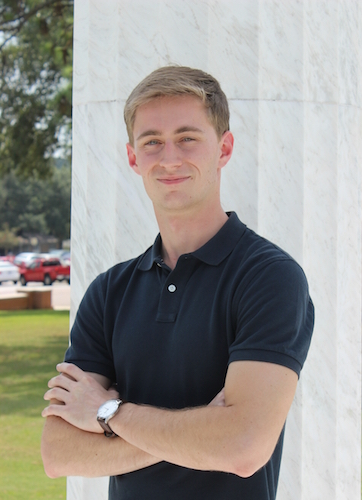 Bryan Chisholm standing outside beside column