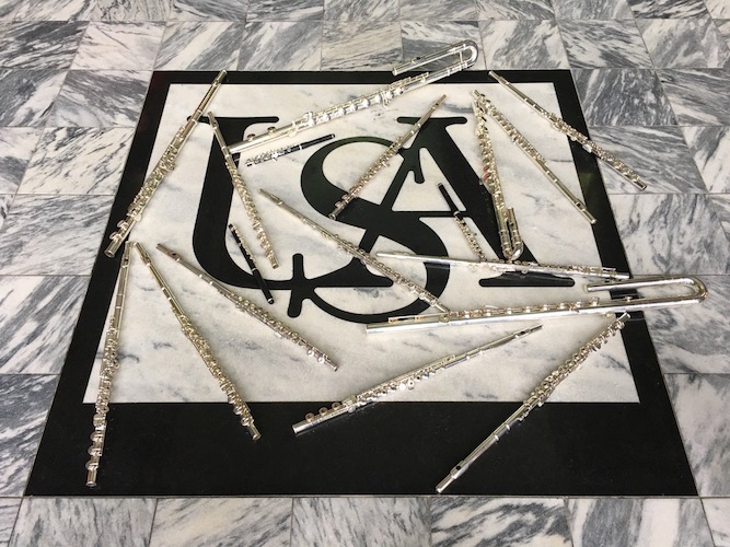 Pictured are silver flutes arranged artistically on the marble floor of the Laidlaw Performing Arts Center lobby. data-lightbox='featured'