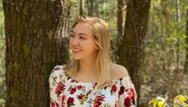 Pictured holding a clarinet while standing in the woods by a pine tree is Cheyenne Higgs.