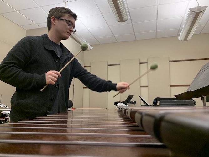 Pictured with mallets in hand playing the marimba is percussionist Kevin Newsome. data-lightbox='featured'