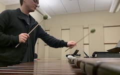 Pictured with mallets in hand playing the marimba is percussionist Kevin Newsome.