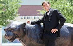 Clark Peterson, pianist, posing outside the USA Mitchell Center with a statue of the Jaguar mascot.