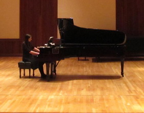 student seated at grand piano