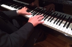 Pictured are two hands playing a Steinway piano.