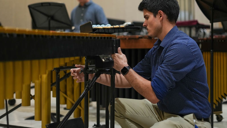 Pictured is percussionist Tyler Scott working on the setup for a concert by the USA Percussion Ensemble. data-lightbox='featured'