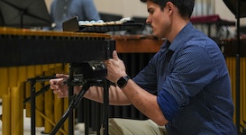 Pictured is percussionist Tyler Scott working on the setup for a concert by the USA Percussion Ensemble.