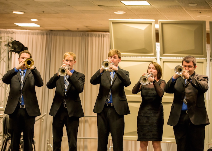 Five members of the USA Trumpet Ensemble standing playing their trumpets.