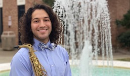 Posing outside by the Laidlaw Performing Arts Center fountain is saxophonist Israel Valenzuela.