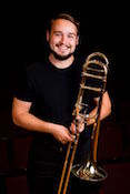 Three trombones pictured laying untended in a pasture of grass.