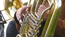 Pictured is a stock photo of a tubist showing only the valve section of the instrument and the hands of an anonymous performer.