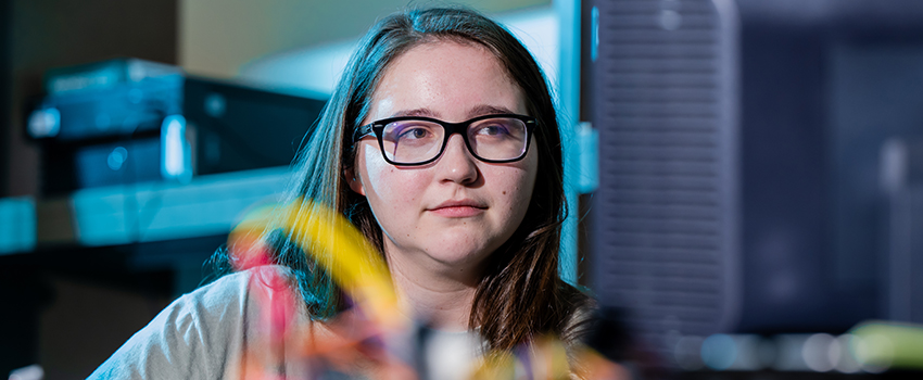 Student with glasses on working on computer.