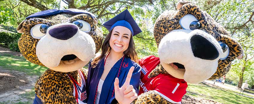 Graduate holding up J hand with Southpaw and Ms. Pawla.