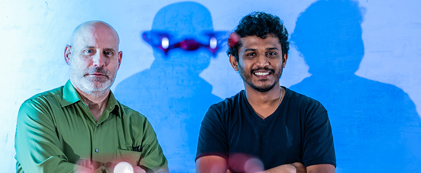 Professor with student with drone flying between them.