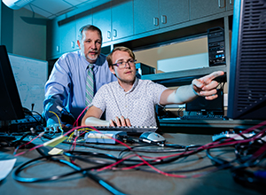 Student working with professor in computer lab.