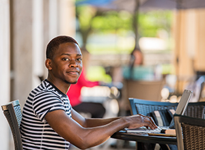 Student working on laptop outside.