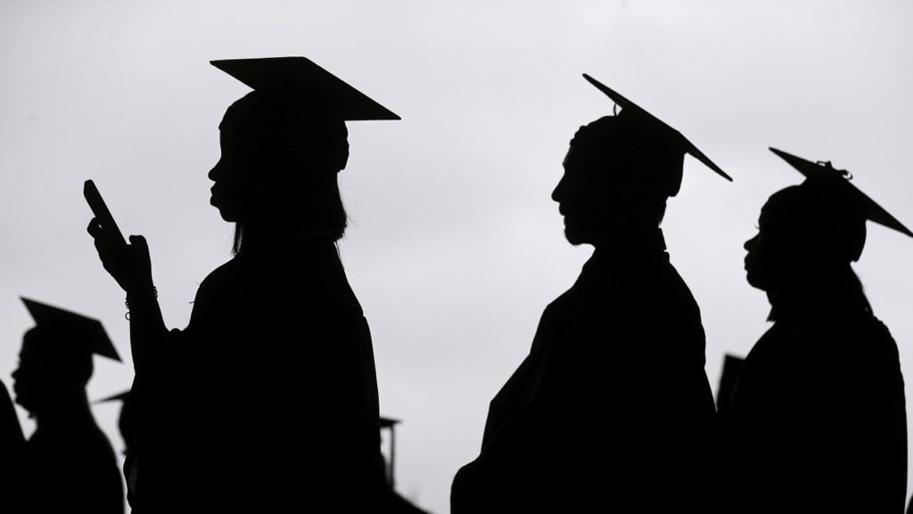 Silhouette of three individuals in cap and gown