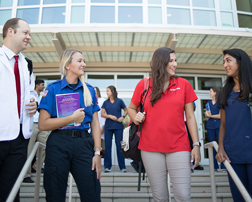 Allied Health students in health uniforms standing outside of the Allied Health building.