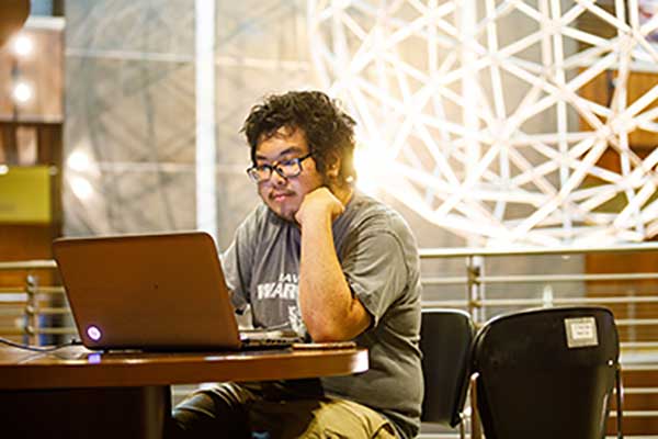Student working on laptop inside of Shelby Hall.