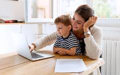 Mom with child in her lap typing on laptop.