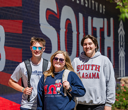 Three students in front of the South mural