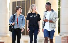 Three students smiling and talking walking outside of Moulton Tower.