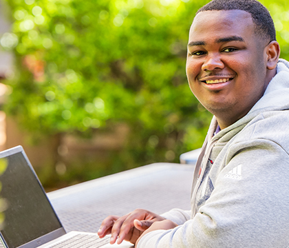 Student working on laptop outside.