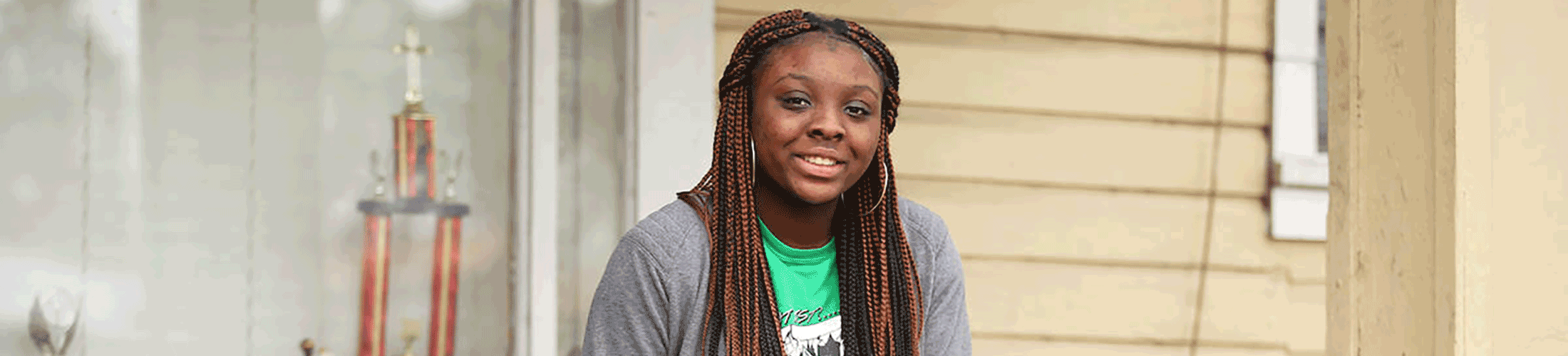 Student sitting on step of house outside.