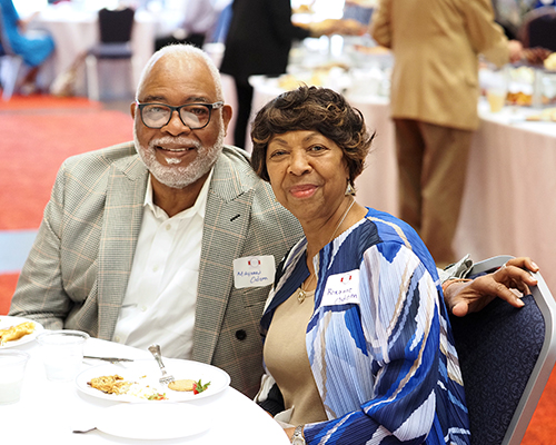 Two alumni sitting at a table in the MacQueen Center at the 1974 Society Reception.