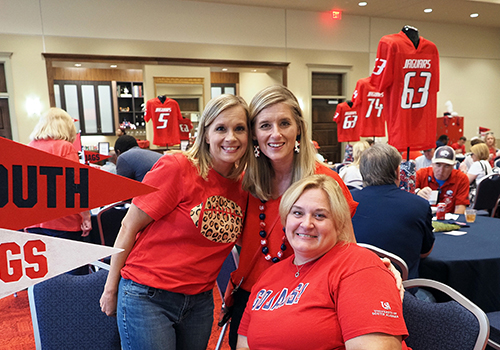 Three alumni members at an event at the MacQueen Center wearing their Jag Gear.