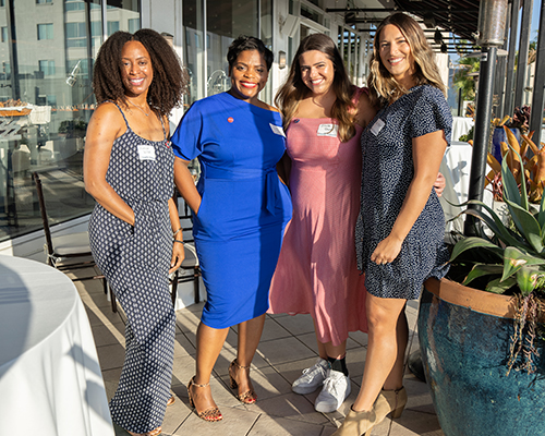 Four female alumni standing outside on porch at Santa Monica event..