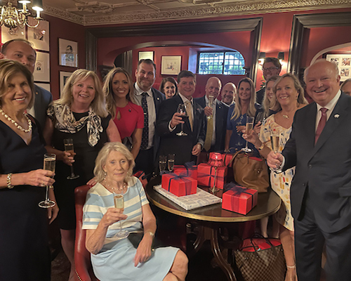 Alumni with President Bonner, Vice President Kent, Margaret Sullican, and Karen Edwards sitting at restaurant holding up glasses of champagne.