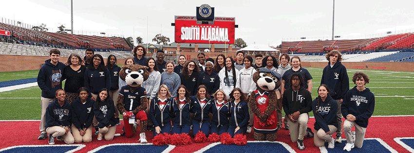 Baker students on football field with cheerleaders and Southpaw and Ms. Pawla.