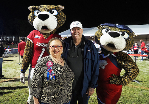 Two alumni members standing with Southpaw and Ms. Pawla.