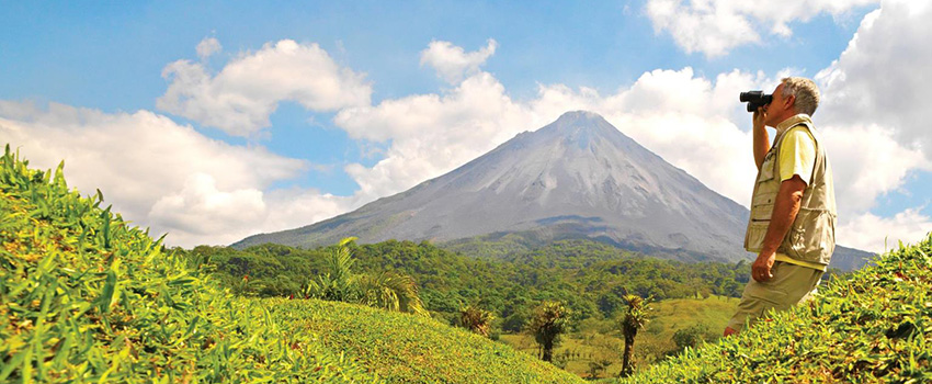 Person looking through binoculars in Costa Rica viewing a mountain.