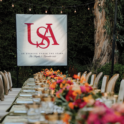 Dining table outside under the lights with the USA sign hanging in the background.