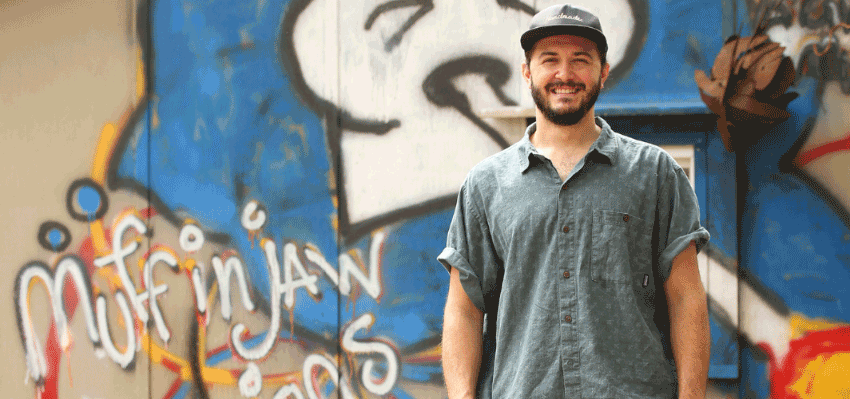 Freddie Blanche in front of graffiti on a wall.