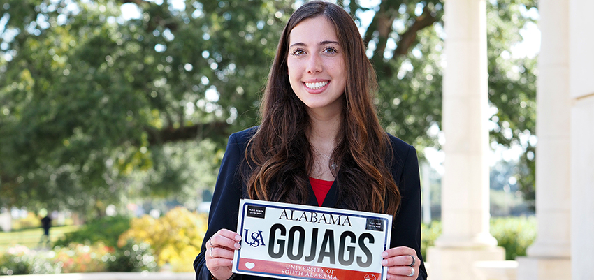 Student holding up Go Jags USA license plate.