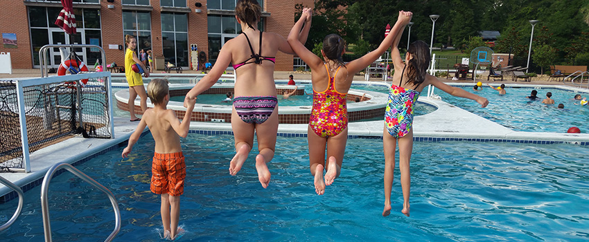 Kids jumping in the outdoor pool at the Student Recreation Center.