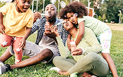 Family playing with bubbles outside on the grass.