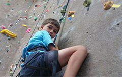 Boy climbing on rock wall.