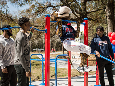 Southpaw doing a pull up the Jag Fitness Trail as students look on.