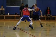 Two male students playing basketball in gym