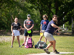 Students playing disc golf on campus.