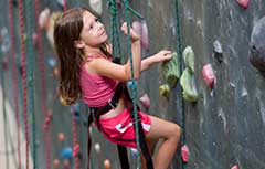 Young girl climbing on rock wall.