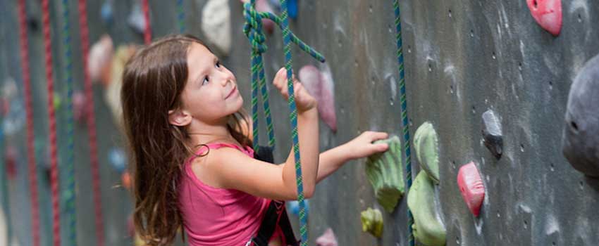 Young girl climbing rock wall.