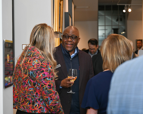 Male alumni holding wine glass smiling talking to woman at Birmingham Alumni event.