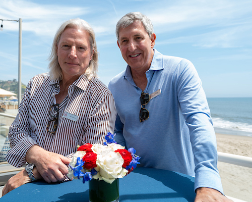 Two alumni in front of beach at Los Angeles Alumni event.