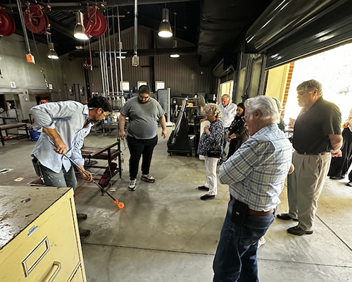 Members of Port City Craftsman watching glass blowing in the studio at USA.