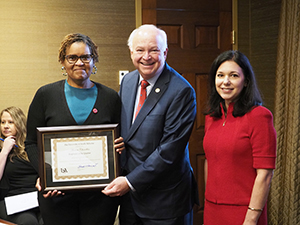 Monica Chambliss holding her award presented to her by President Bonner and Kelly McCarron.