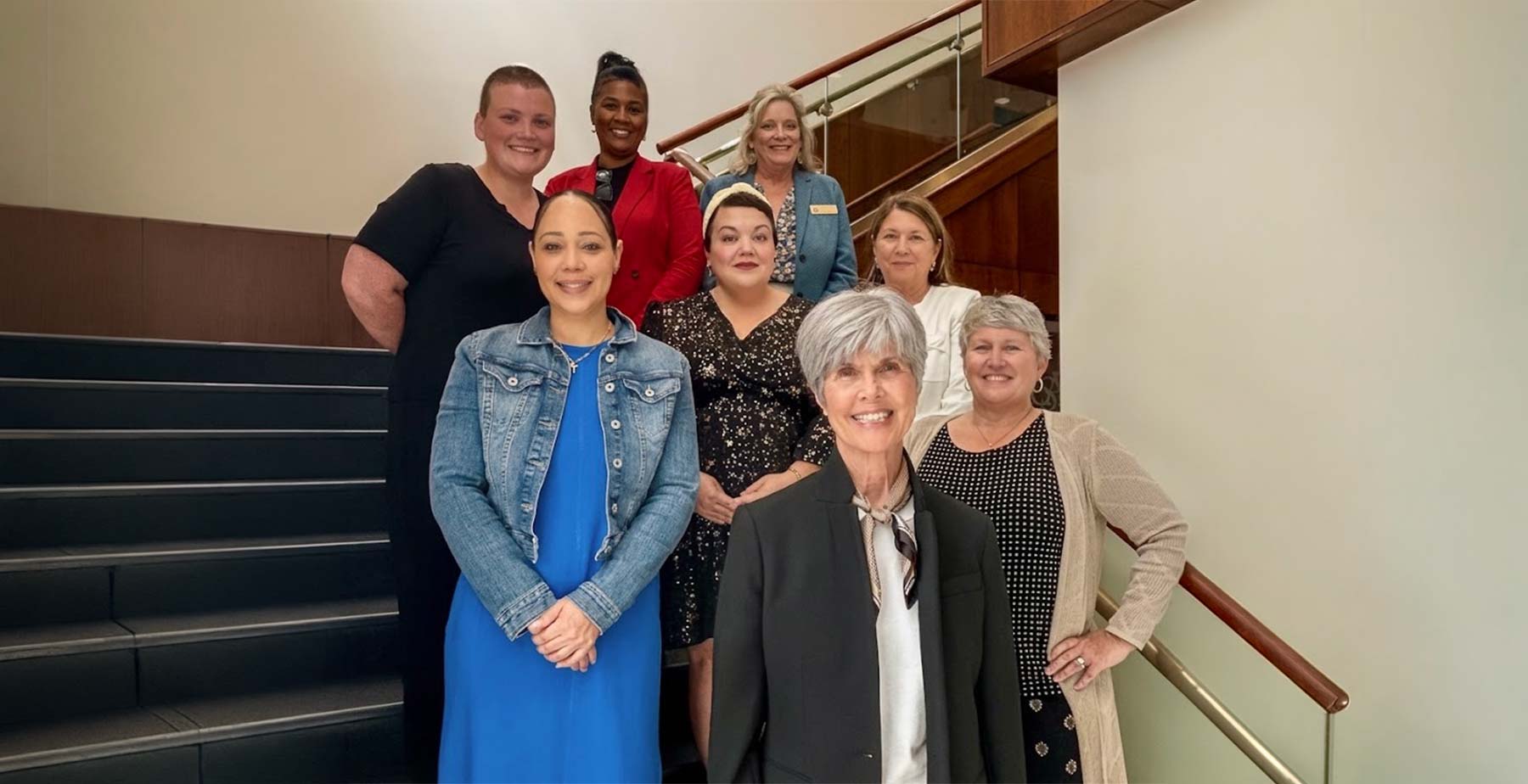 Members of the USA College of Nursing EMPOWERED Program grant team smiling together on a staircase inside the Health Sciences Building. data-lightbox='featured'